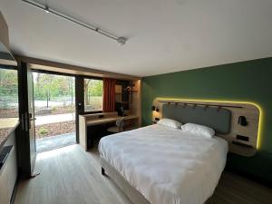 a bedroom with a large bed and a green wall at Campanile NATURE - Clermont-Ferrand Nord Riom in Riom