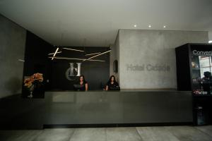 Dos mujeres de pie en el mostrador de una oficina de hotel. en Hotel Cidade Araxá, en Araxá