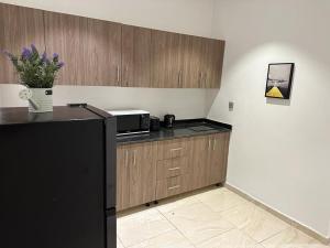 Una cocina con gabinetes de madera y un refrigerador negro. en Bark luxury apartments Abidjan Attoban 2, en Abiyán