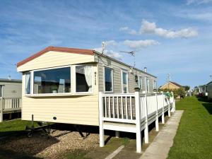 ein weißes Haus mit einer Veranda und einem Zaun in der Unterkunft Meadow View 158 - Golden Palm, Pet friendly, WiFi, bed linen - Meadow Lakes Caravan & Lodge Hire in Skegness