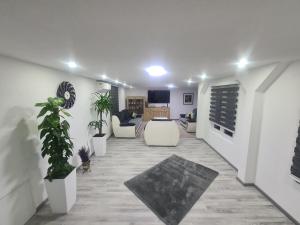 a living room with white furniture and potted plants at Villa maskara in Bihać