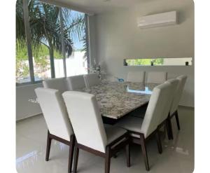 a dining room with a table and white chairs at Casa cascada candela in Bahías de Huatulco