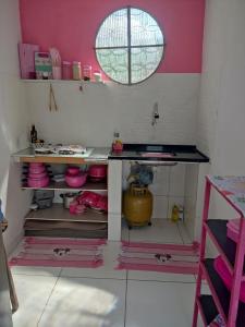 eine Küche mit rosa Wänden und einem Tisch in einem Zimmer in der Unterkunft aconchegante casa - lagoinha in Nova Iguaçu