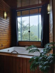 una vasca da bagno in una stanza con una finestra di Casa Visconde 2 a Visconde De Maua Altre 112 foto