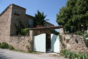 a house with a white gate and a stone wall at Le Jas des Nevières in Pierrerue