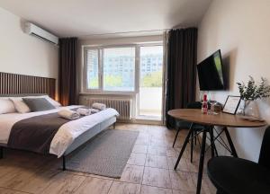 a bedroom with a bed and a table and a window at New cozy studio, AC & Balcony in Bratislava