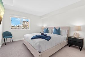 een witte slaapkamer met een bed en een blauwe stoel bij Sunlit Marina View 2BR - Blue Agate Seaside Gem in Los Angeles