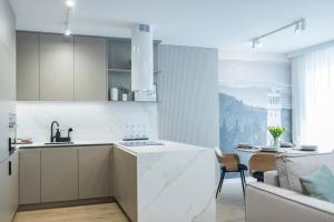 a kitchen with white cabinets and a dining room at Apartamenty SOWIE SZCZYTY in Dzierżoniów