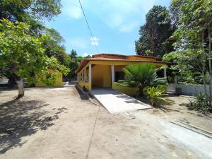 a small yellow house with a driveway at La Fortaleza Marapanim in Marapanim