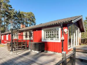 a red tiny house on a wooden deck at 7 person holiday home in Mönsterås in Mönsterås