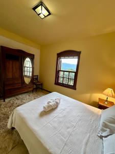 a bedroom with a white bed with a window at Casa Rústica - 3 vagas de garagem - Pet Friendly com vista para Serra de São José in Tiradentes