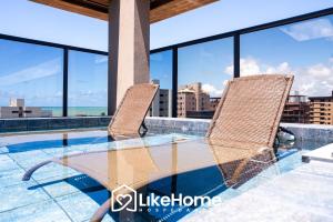 a glass table and two chairs on the roof of a building at Vivir Maria Paula - Intermares in Cabedelo