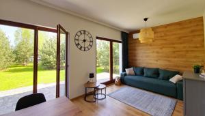 a living room with a couch and a clock on the wall at Sosnowa Kępa in Żdżar