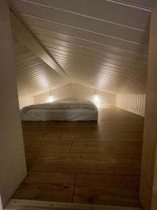 a bed in a small room with a wooden floor at Nybyggd stuga nära centrum och tågstation in Falkenberg