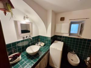 a green tiled bathroom with a sink and a toilet at Sto al Trullo - Historic Trullo with Private Jacuzzi and Sauna in Martina Franca +27 photos