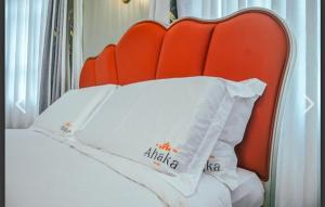 a bed with an orange headboard and two white pillows at Ahaka cottages mbarara in Mbarara