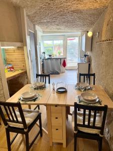 a large wooden table with chairs and a kitchen at Troglodyte du Petit Coteau in Vouvray