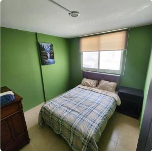 ein grünes Schlafzimmer mit Bett und Fenster in der Unterkunft Rinconada Cabrera in Atlixco