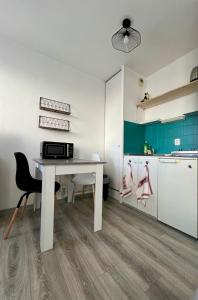 eine Küche mit einem weißen Tisch und einem Kühlschrank in der Unterkunft Studio calme proche de la gare in Amiens
