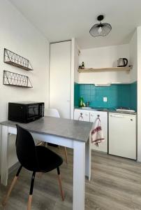 eine Küche mit einem weißen Tisch und einem schwarzen Stuhl in der Unterkunft Studio calme proche de la gare in Amiens