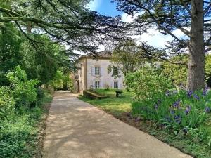 a path leading to a large stone house with purple flowers at La Reverdie in Cahuzac-sur-Vère