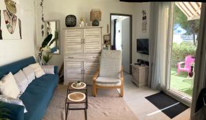 Una sala de estar con un sofá azul y una silla. en Plain pied - Appartement dans résidence sous les pins, en Cap d'Agde 3 fotos más