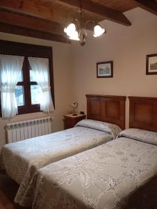 a bedroom with two beds and a window at Apartamentos Picos de EUROPA in Dego