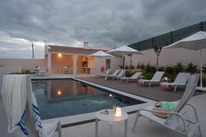 a swimming pool with chairs and umbrellas next to a house at Vila Marta - Garça Real in Vila Franca do Campo