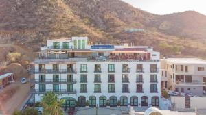 a large white building in front of a mountain at The Residences Apart-Hotel By Morgan in Cabo San Lucas