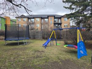 two playground equipment in a yard with a building at Stay & Play - Central Family Friendly in Calgary