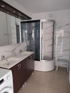 a bathroom with a shower and a sink and a washing machine at Czysta Dolina in Baciki Bliższe +11 photos