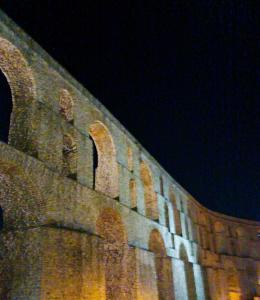 a brick building with a wall with arches at night at The SPiTi Project 23 in Kavála