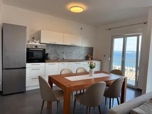 a kitchen with a table and chairs and a kitchen with a view at Apartment Marino 2 in Duće