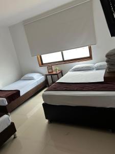 a bedroom with two beds and a window at Hotel Terraza in Buga +7 photos