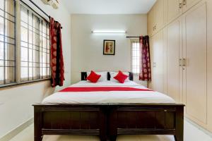 a bedroom with a large bed with red pillows at Hotel O J2 Service Apartment in Chennai +47 photos