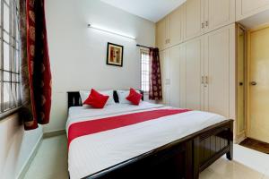 a bedroom with a large bed with red pillows at Hotel O J2 Service Apartment in Chennai