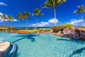 a swimming pool with a waterfall and palm trees at Totally Revamped Pacific Paradise J505 At Wbv! -Top Floor Ocean Views! in Wailea