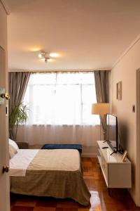Un dormitorio con una cama y una ventana grande. en Steps from Costanera Center, en Santiago