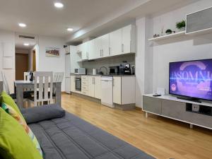 ein Wohnzimmer mit einem TV und einer Küche in der Unterkunft Sunrise Beach Apartment Playa Puerto de Sagunto in Puerto de Sagunto