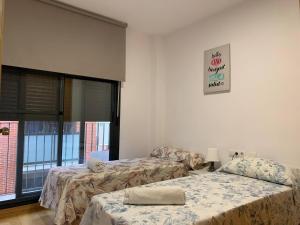 ein Zimmer mit zwei Betten und einem Fenster in der Unterkunft Sunrise Beach Apartment Playa Puerto de Sagunto in Puerto de Sagunto