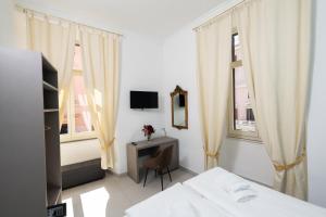 Un dormitorio con una cama y un escritorio y dos ventanas. en Alida Rooms, en Roma