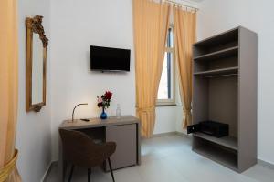 Una habitación con un escritorio con televisión y una ventana. en Alida Rooms, en Roma