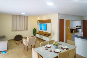 a living room with a dining table and a kitchen at 4 quartos, sendo 2 suítes - uma com varanda privativa, a 700m da Praia da Boca da Barra e 2,5km da orla de Tamandaré, Wifi 200MB e cozinha completa - Piscina e estacionamento privativos - Ideal para grupos e famílias - tranquilo para home office in Tamandaré