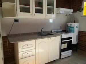 a kitchen with white cabinets and a sink and a stove at Cabañassoleado Villa Cura Brochero in Villa Cura Brochero +9 photos