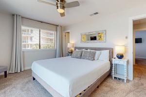a bedroom with a white bed and a window at Beach Bahr Den in Santa Rosa Beach