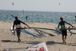 a group of people walking on the beach with their surfboards at Hostal Brisa Marina in Port d'Alcudia