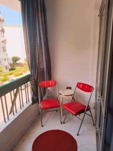 two red chairs and a table on a balcony at Gadou Rooms -Private & Shared Stays in Port Said Best Location in Port Said