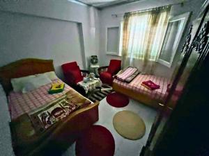 a bedroom with a bed and two red chairs at Gadou Rooms -Private & Shared Stays in Port Said Best Location in Port Said
