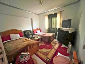 a bedroom with two beds and a flat screen tv at Gadou Rooms -Private & Shared Stays in Port Said Best Location in Port Said