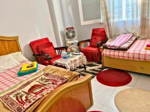 a bedroom with red chairs and a bed and a table at Gadou Rooms -Private & Shared Stays in Port Said Best Location in Port Said